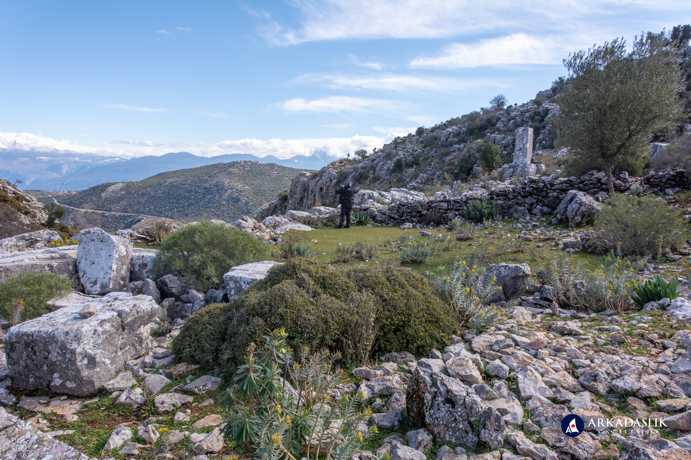 Visitor standing at the base of the Sidyma acropolis overlooking the valley