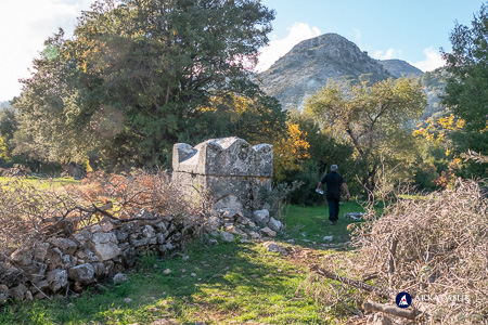 Visitor walking past a hip-style Lycian tomb at Sidyma
