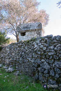 Tall monumental tomb rising above a stone wall at Sidyma