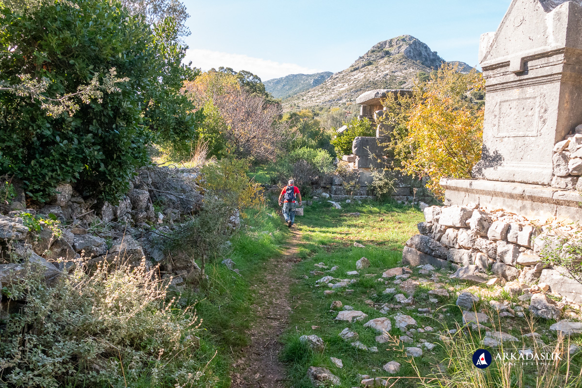 Man walking along a footpath beside monumental tombs.